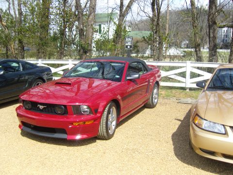 2007 Ford Mustang - Red 2007 Ford Mustang convertible with black top, parked outdoors.