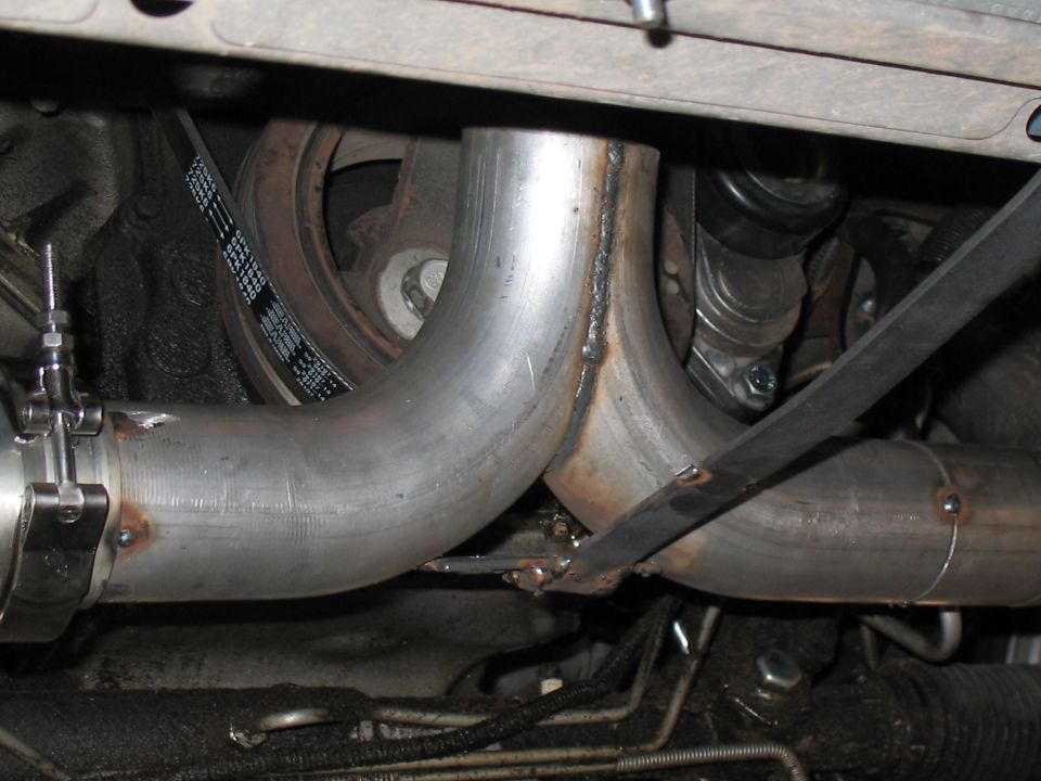 Custom exhaust pipes and serpentine belt visible under a vehicle