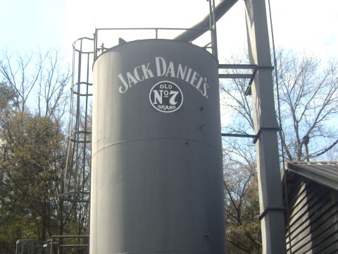 2007 Ford Mustang - A large industrial silo prominently displays the Jack Daniel's Old No. 7 Brand logo against a backdrop of trees and a clear sky.