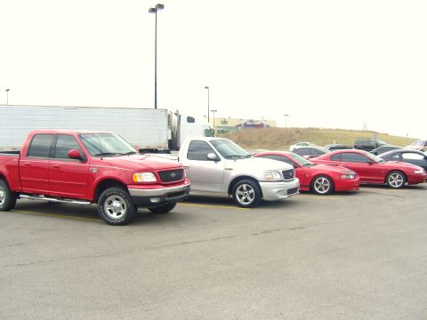 2007 Ford Mustang - A red 2007 Ford Mustang is visible in a parking lot alongside other cars and trucks.