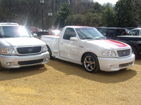 2007 Ford Mustang - Two Ford F-150 pickup trucks, one a white Lightning model, are parked side-by-side.