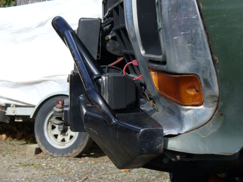 1978 Ford Bronco - Close-up of a black aftermarket front bumper with a winch and trailer hitch assembly, with a trailer visible in the background.