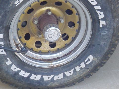 1982 Ford Bronco - Close-up of a wheel a gold rim and a MileMarker automatic hubcap, with "Chaparral" tire lettering visible.