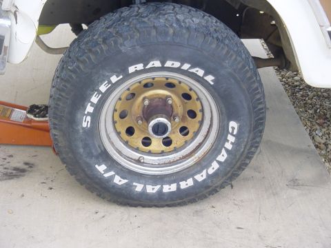 1982 Ford Bronco - A close-up view of a Chaparral A/T steel radial tire mounted on a gold-colored wheel.
