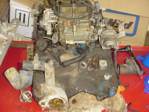 1982 Ford Bronco - Close-up of a dirty engine intake manifold and carburetor assembly, likely undergoing maintenance.
