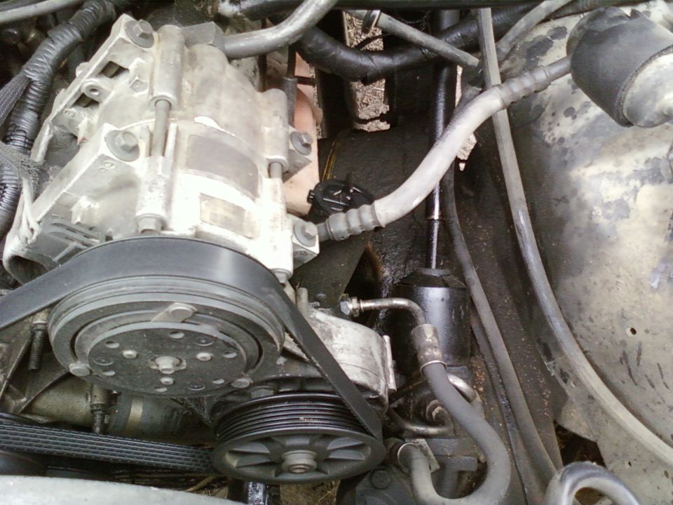close-up of engine parts, including compressor and pulleys