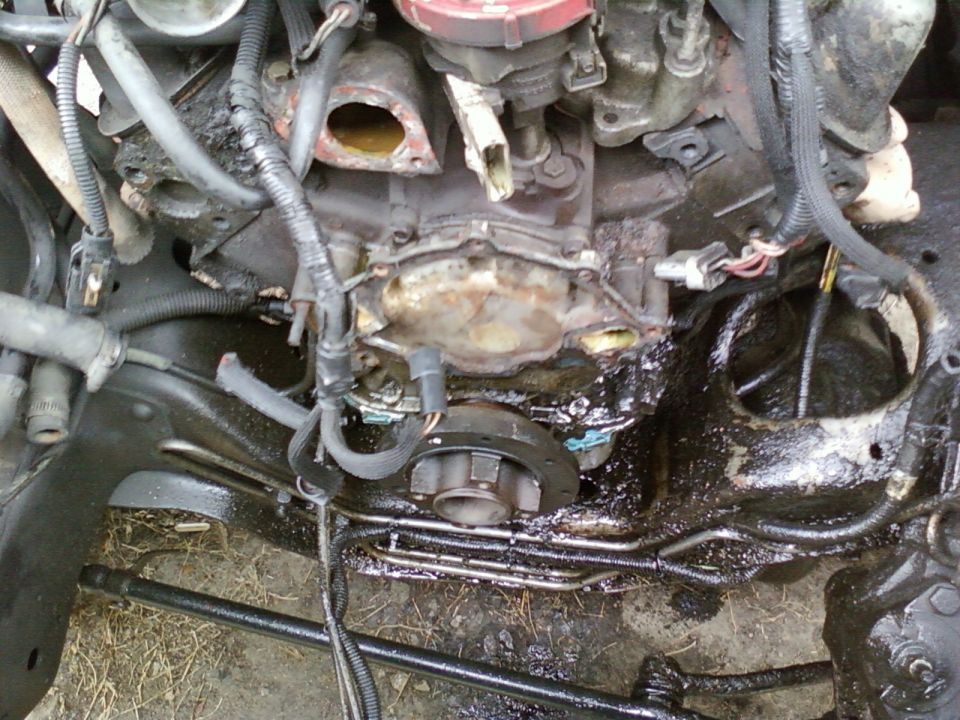 Engine block with oil leaks and various hoses and wires attached