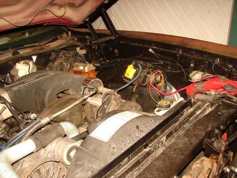 1973 Ford Ranchero - Open engine bay of an older V8 vehicle photographed from the front, showing the black plastic "CAUTION FAN" fan shroud, radiator hoses, alt…