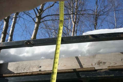 1990 Chevrolet Suburban - A yellow measuring tape is held vertically over a metal rack with snow on it. The tape shows measurements in inches, with the top visible m…