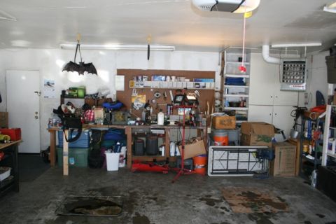 1990 Chevrolet Suburban - This is an image of a cluttered garage with a workbench, shelves, and various tools and storage items. A decorative bat hangs from the ceil…