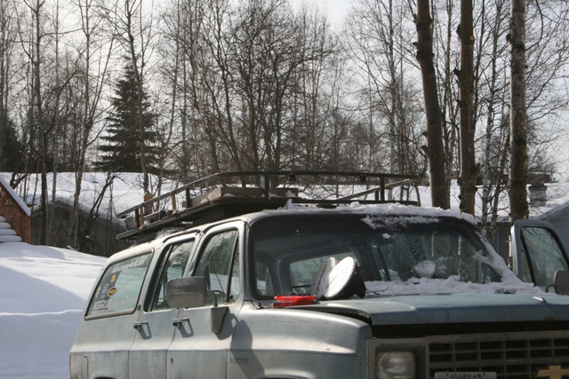 Light blue Chevrolet Suburban with roof rack in snow
