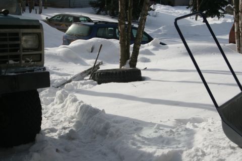 1990 Chevrolet Suburban - A dark colored SUV is partially buried in snow next to a dark colored truck. A tire and a shovel are visible in the snow between the vehicl…