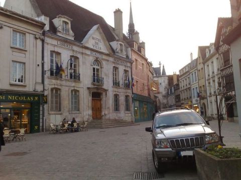1991 Ford LTD Crown Victoria - Photograph of a French town square and SUV, not a technical document.