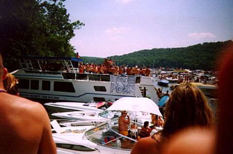 1982 Ford Bronco - A large gathering of boats and people on the water, with a banner on one boat displaying 'LIVE PORN'.