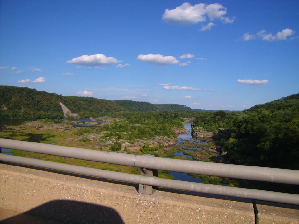 River valley with hills and a bridge railing in the foreground.