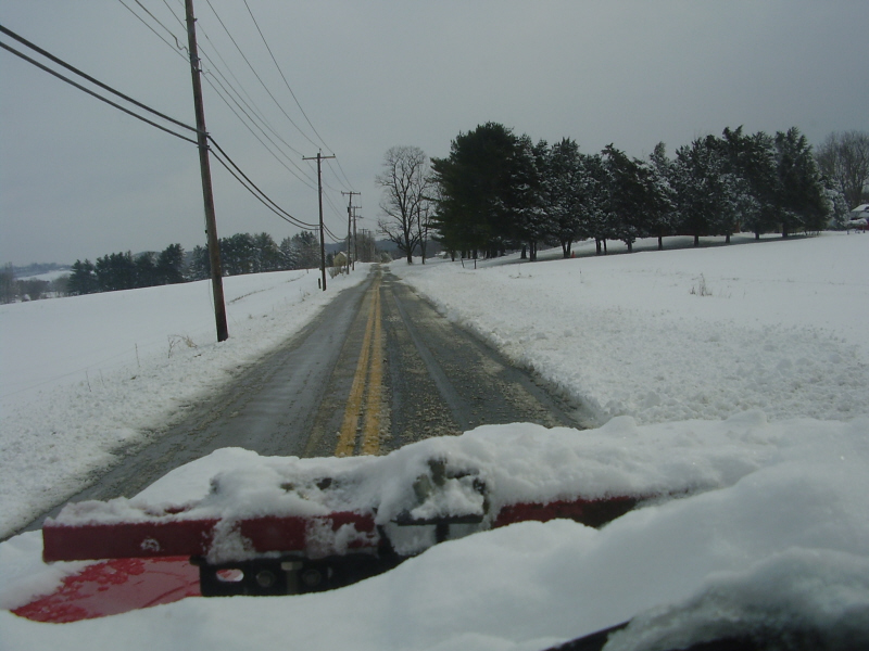 Snowplow on a snowy road in a rural area.
