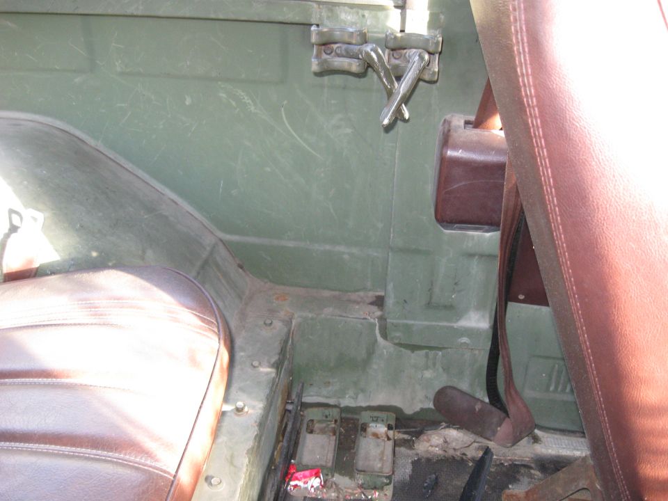 Interior of a vintage green vehicle showing pedals and seat base.
