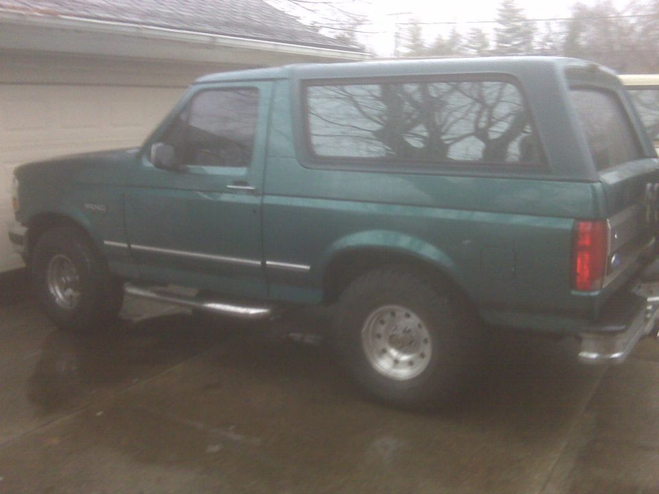 Teal green Ford Bronco full-size SUV parked on a driveway by a garage