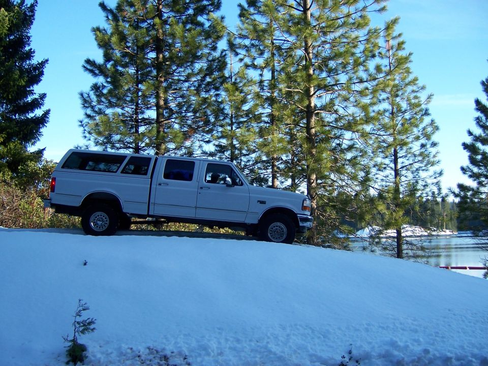 Photo of a white crew-cab truck in snow beside a lake