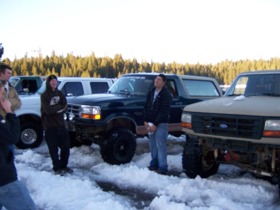 Photo of people standing among lifted trucks in the snow