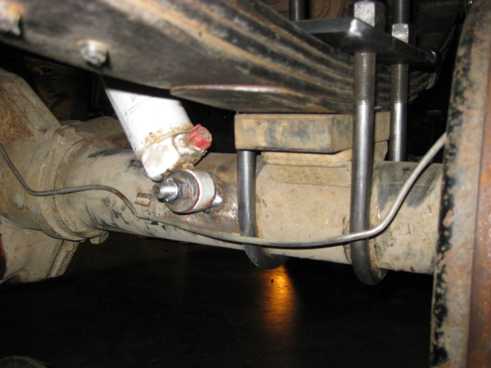 Close-up of rear axle suspension with leaf springs, U-bolts, and shock absorber.