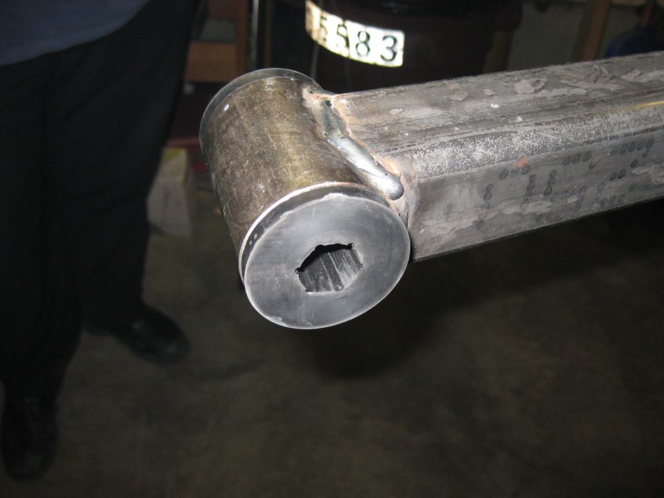 Close-up of a metal part with a hexagonal opening, welded to a bar.