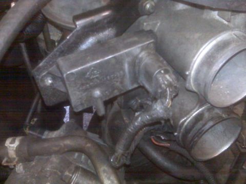 1995 Ford Bronco - This close-up photo shows a section of an engine bay, focusing on the throttle body and associated sensors and wiring. The metal components…