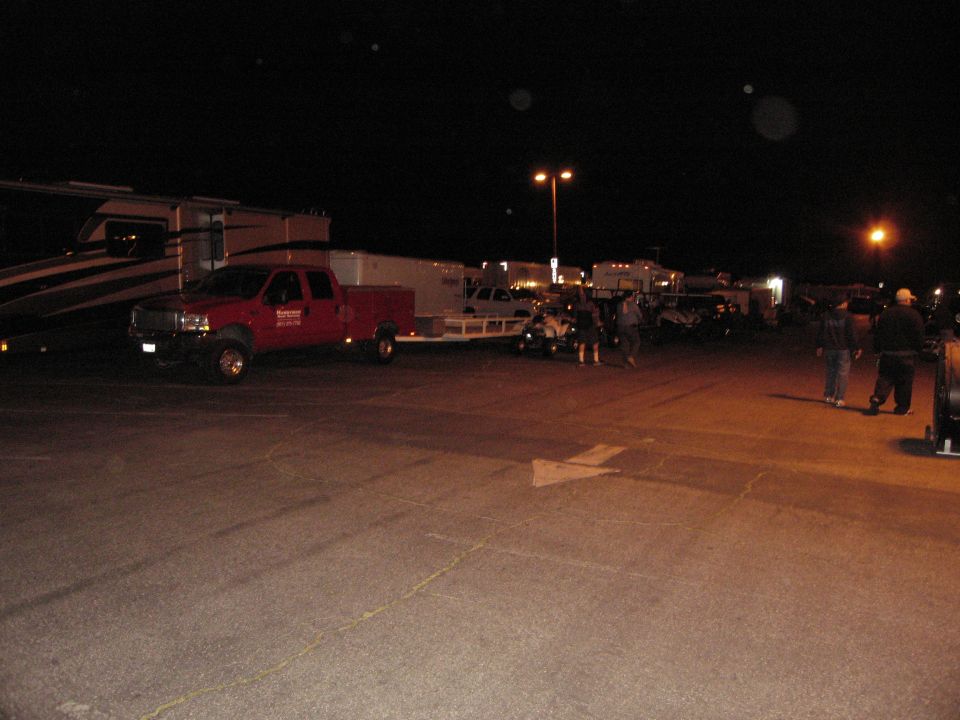 Red Ford F-Series pickup truck towing a trailer at night next to an RV.