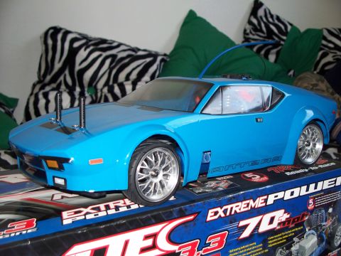 1990 Ford Bronco - A bright blue remote-controlled car, resembling a classic sports car, is displayed on top of its packaging box. The car features silver rim…