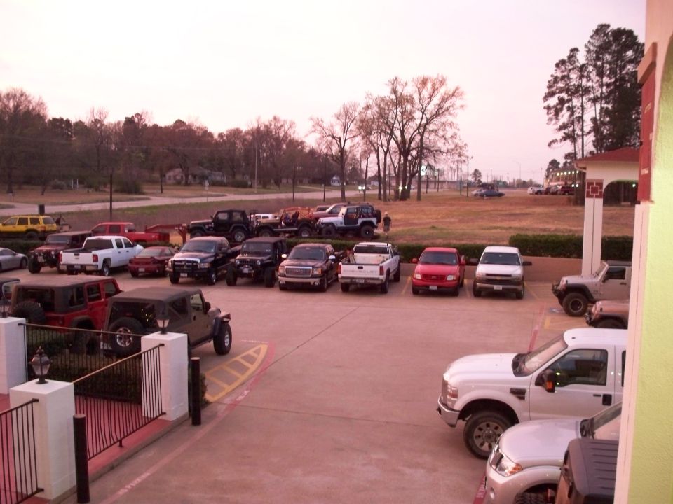 Various Jeeps and pickup trucks parked in a lot.