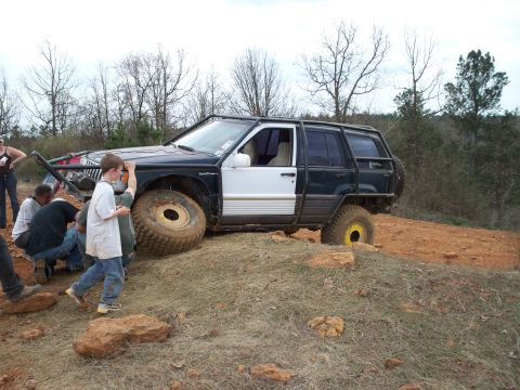 1996 Ford Bronco - A heavily modified Jeep Grand Cherokee navigates a challenging off-road course with assistance from onlookers.