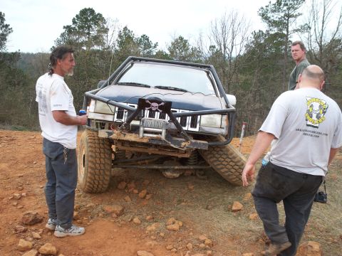 1996 Ford Bronco - Modified Jeep Grand Cherokee with winch and roll cage on an off-road trail.
