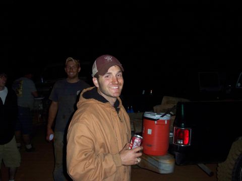 1996 Ford Bronco - A group of people and vehicles are gathered at night, with one man in the foreground holding a soda.