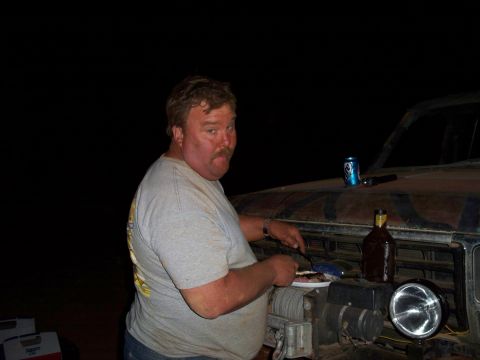 1996 Ford Bronco - Man grilling next to a vehicle at night.