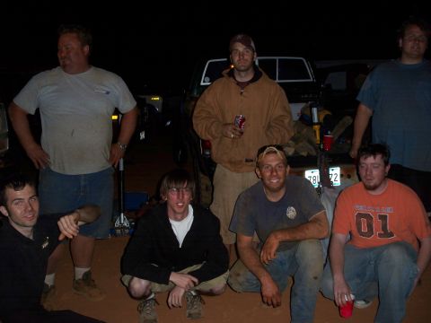 1996 Ford Bronco - A group of men pose for a photo with trucks in the background at an outdoor event.