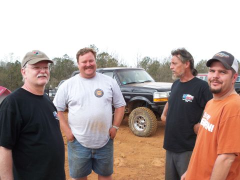 1996 Ford Bronco - A group of men stand in front of a modified black Ford Bronco during an outdoor event.