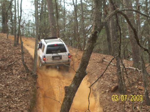 1996 Ford Bronco - SUV navigates a steep, dusty trail in a wooded area. Date stamp reads 03/07/2009.