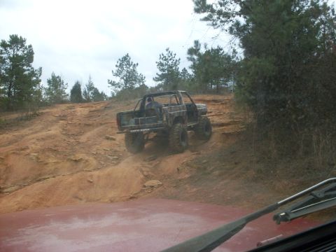 1996 Ford Bronco - This heavily modified off-road vehicle navigates a steep, sandy incline on a trail.