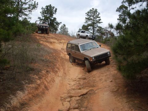 1996 Ford Bronco - Multiple SUVs navigating a challenging off-road trail on a cloudy day.