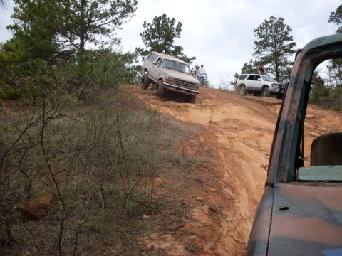 1996 Ford Bronco - Multiple off-road vehicles navigate a challenging dirt trail on a cloudy day.