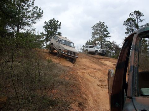 1996 Ford Bronco - Several off-road vehicles navigate a steep, sandy incline on a cloudy day.