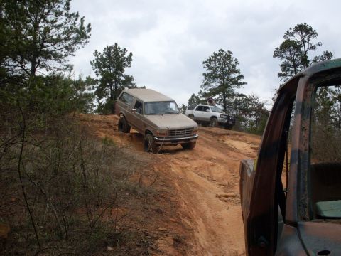 1996 Ford Bronco - A tan Ford Bronco navigates a steep dirt incline with other vehicles in the background.