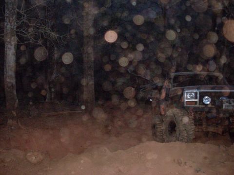 1996 Ford Bronco - An off-road vehicle navigates a dirt path at night, illuminated by its headlights.
