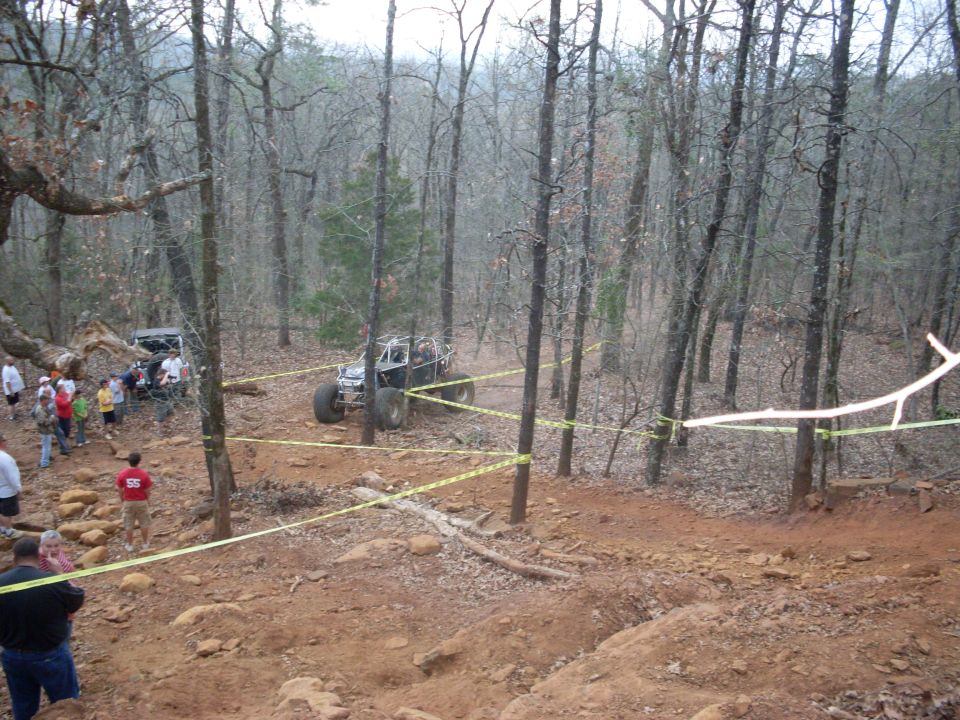 off-road buggy navigating a wooded trail with spectators watching