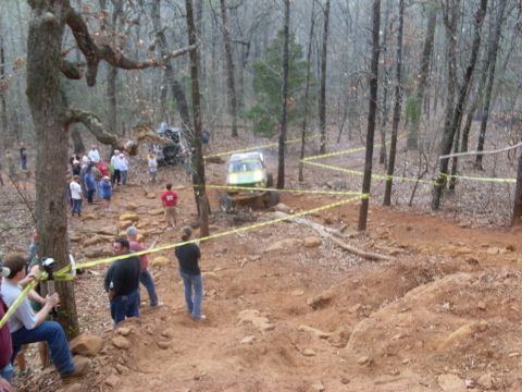 1996 Ford Bronco - Spectators watch as off-road vehicles navigate a challenging course marked with yellow caution tape.