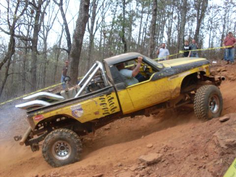 1996 Ford Bronco - Modified pickup truck navigates a challenging off-road course with spectators watching.