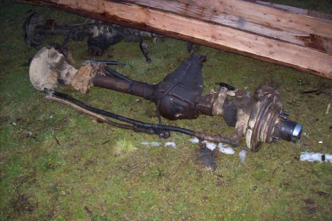 1995 Ford Bronco - Vehicle axles and differential housings are visible on the ground, with wooden planks in the background.