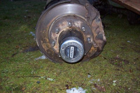 1995 Ford Bronco - A close-up view of a rusty truck hub and brake assembly with a WARN locking mechanism is shown on the ground.