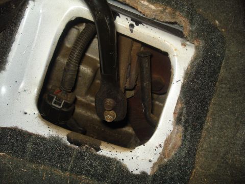 1991 Ford Bronco - This image shows a close-up view of the interior floor of a vehicle, revealing mechanical components and wiring beneath the carpet.