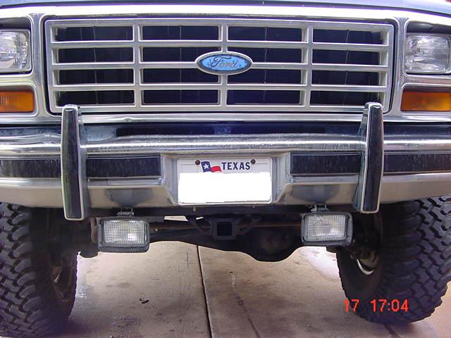 Front grille and bumper of a Ford truck with blue oval emblem and a Texas license plate frame